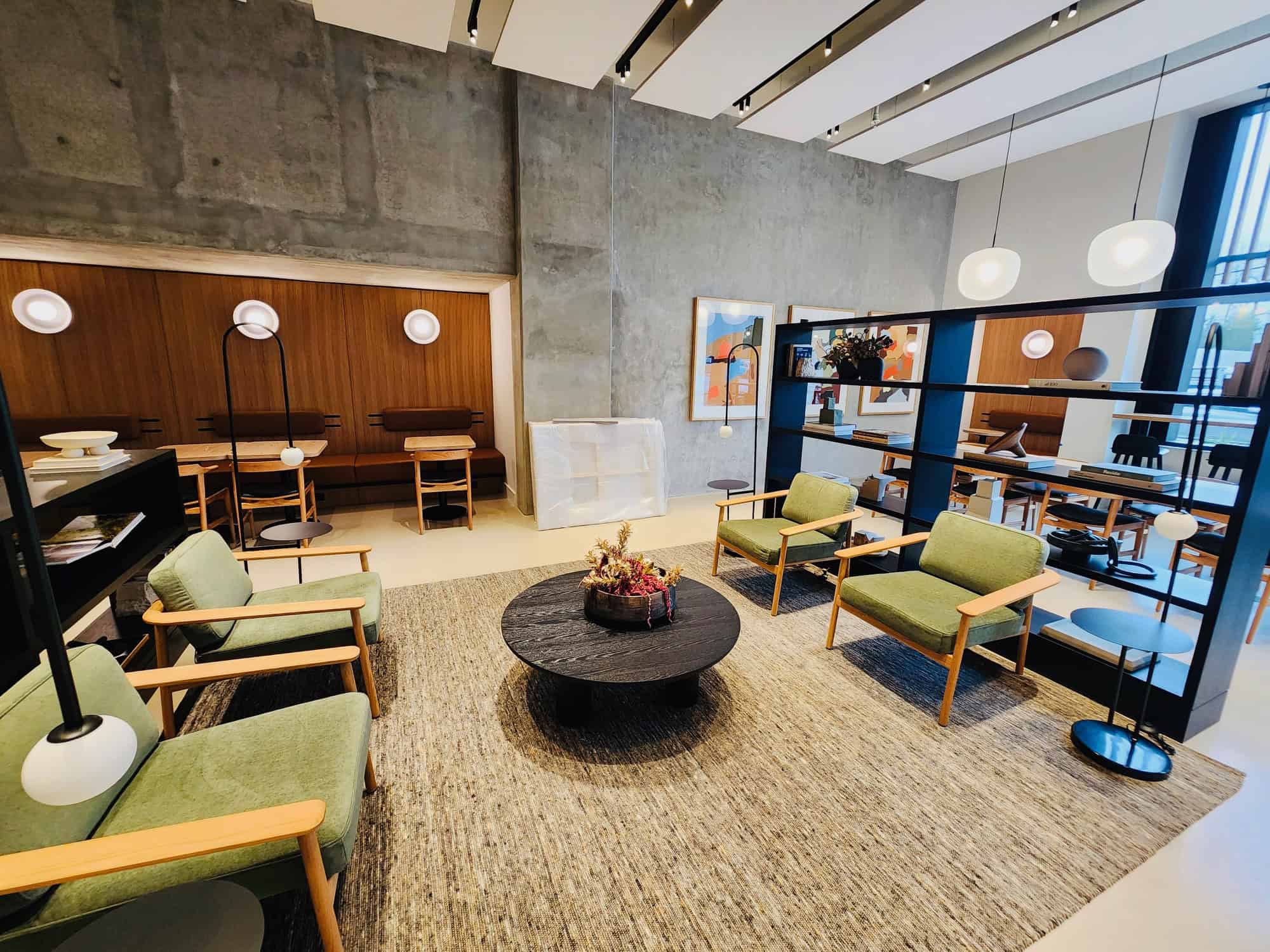 Bright and modern office lounge with stylish seating, contemporary decor, and open shelving, perfect for casual meetings or relaxation in a professional real estate environment.