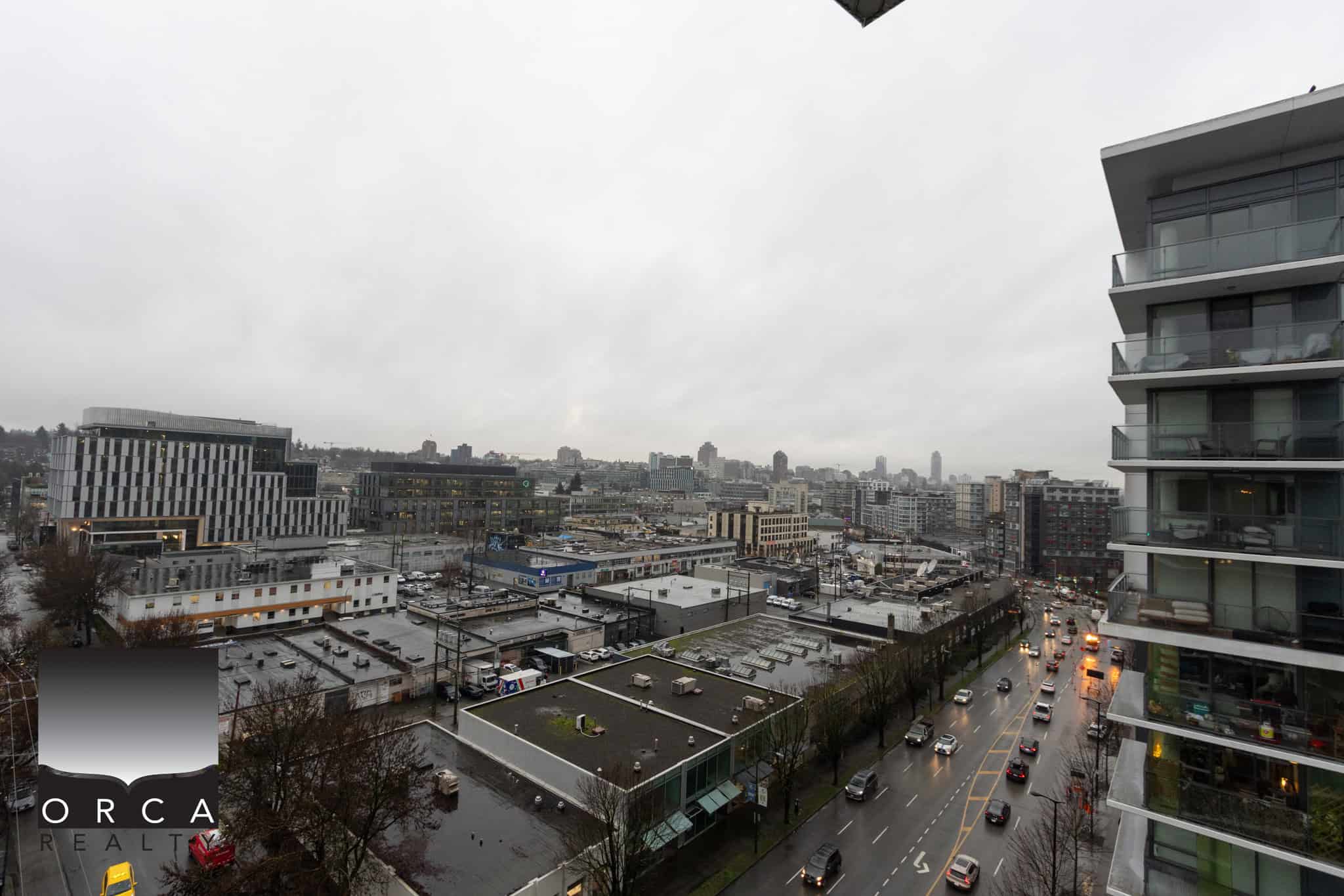 21 (2) Overcast cityscape view from a high-rise apartment balcony in Vancouver, BC, showcasing urban buildings, busy streets, and modern architecture, perfect for real estate and property market visuals in Canada.