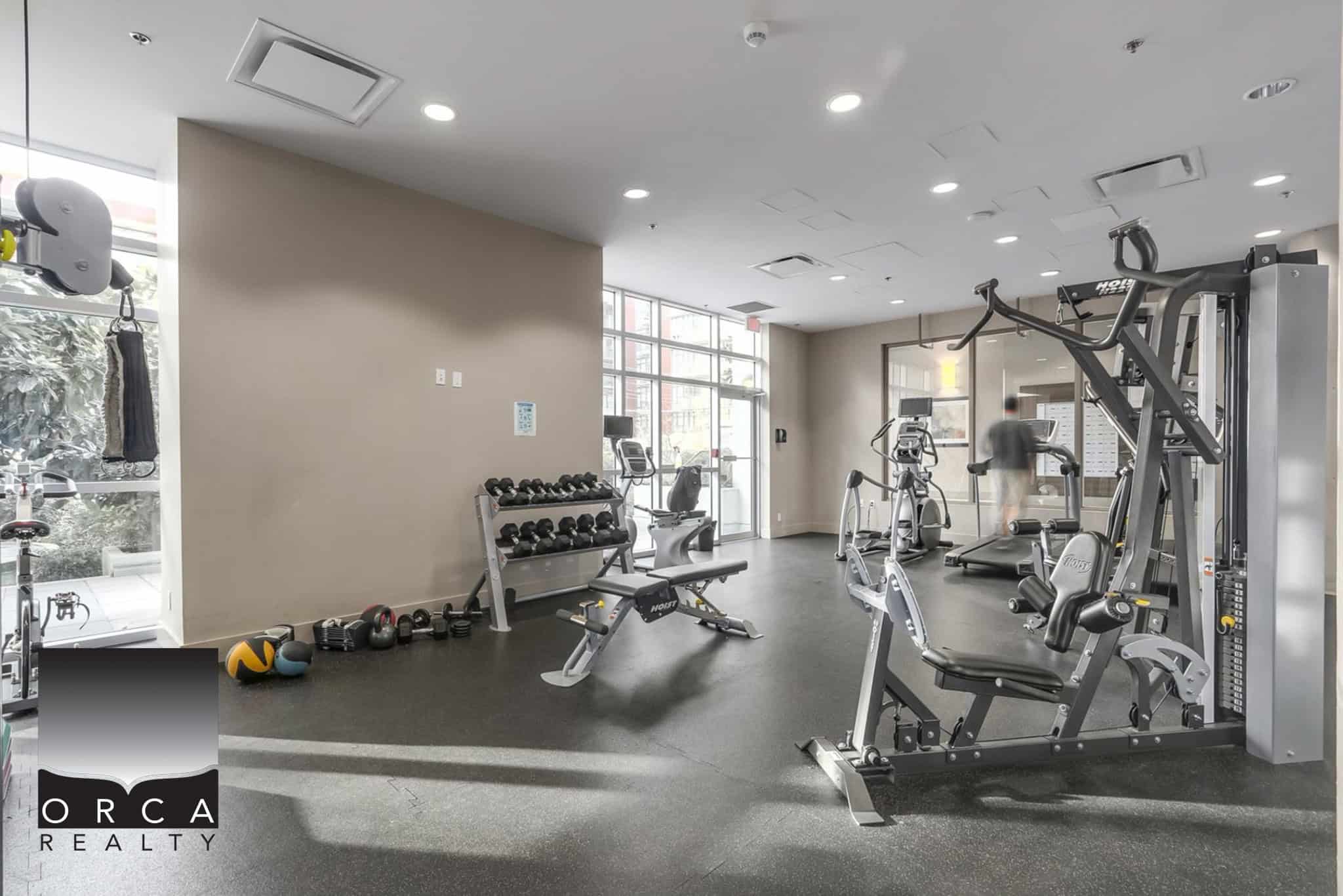 22 (4) Modern gym facilities at Orca Realty Inc. property offering high-quality workout equipment for residents, including free weights, cardio machines, and strength training gear in a bright, spacious environment.