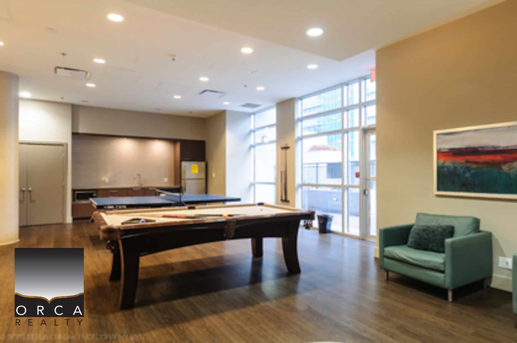 23 (2) Modern, spacious indoor recreational area with billiards and ping pong tables, ample natural light from large windows, stylish seating, and contemporary art, perfect for social gatherings and leisure.