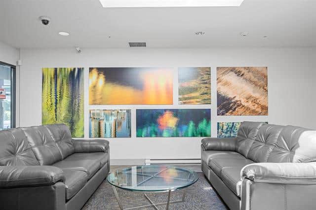 Bright modern real estate office with contemporary art displays and comfortable leather sofas, perfect for client consultations at Orca Realty Inc., your trusted Vancouver property experts.
