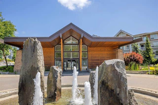 1. Modern waterfront community centre with large glass windows, wooden architecture, and stone fountain, located in Orca Realty's prime Vancouver Island neighbourhood.