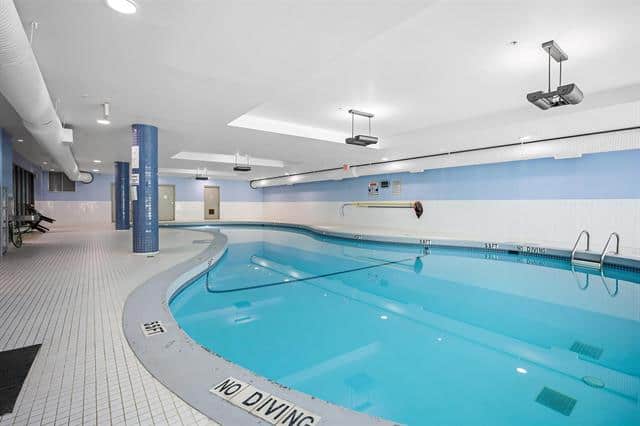Indoor heated swimming pool at Orca Realty Inc. property, ideal for relaxation and fitness, featuring clean water, modern lighting, and safety features, perfect for health-conscious residents.