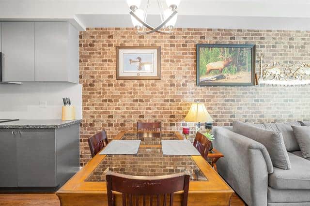 Bright dining area with brick wall, wooden table, and cozy living room; ideal for Vancouver-based real estate and property listings in BC.