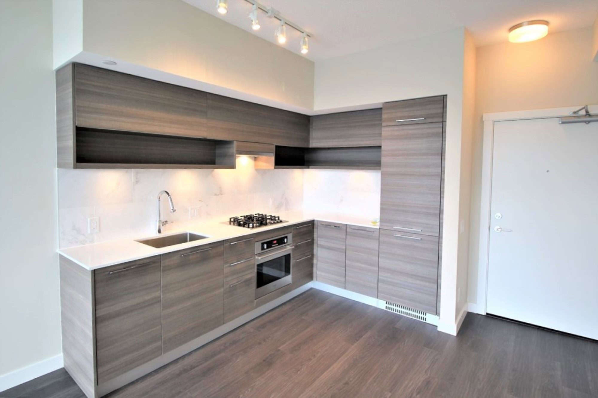 Modern grey kitchen with built-in appliances and sleek cabinetry, ideal for Toronto real estate listings. Stylish new kitchen design perfect for condo or apartment homes in Vancouver.