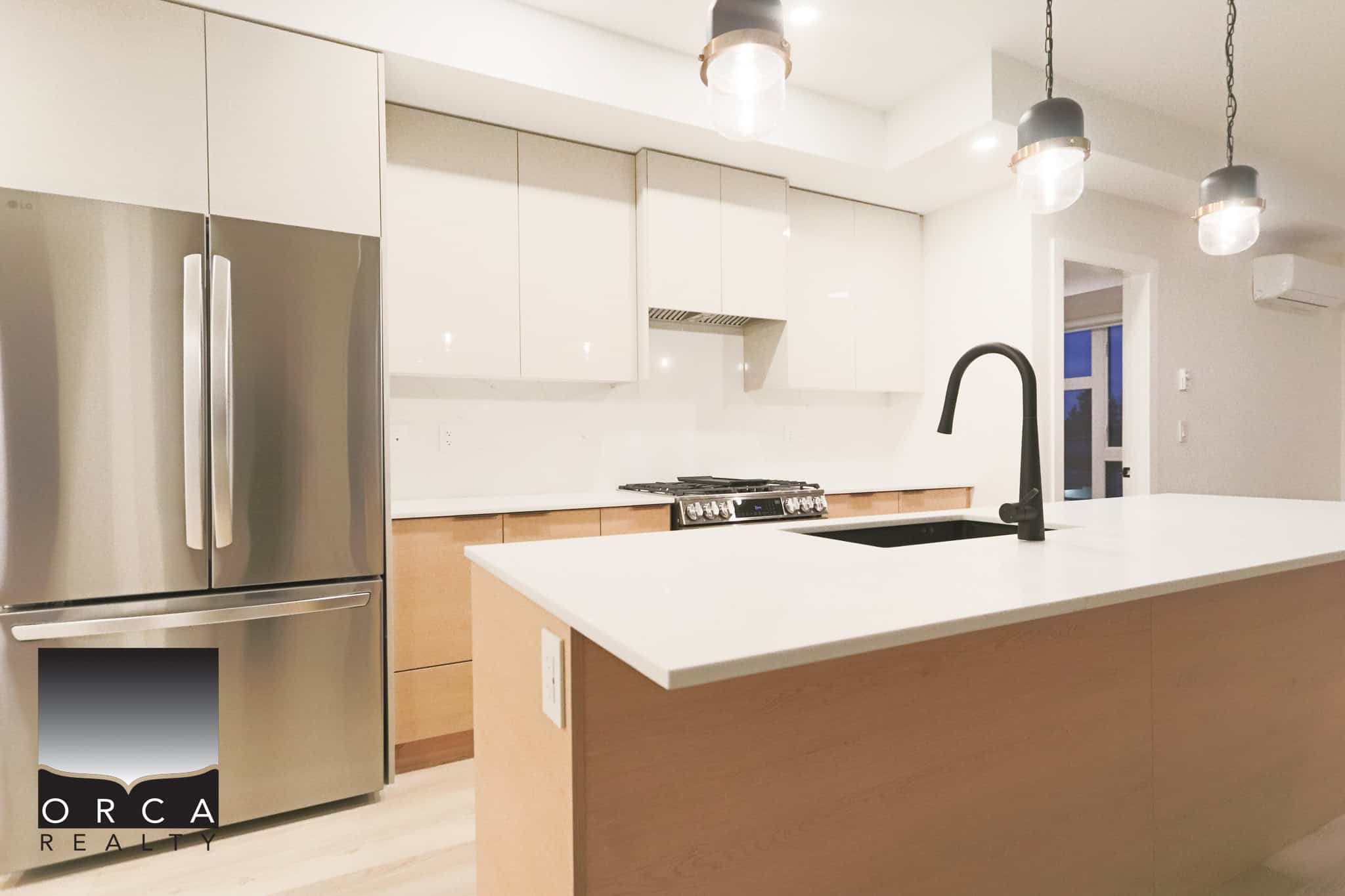 Bright modern kitchen featuring stainless steel appliances, sleek white cabinetry, and a spacious island with black faucet, ideal for Toronto-area homebuyers seeking contemporary comfort.