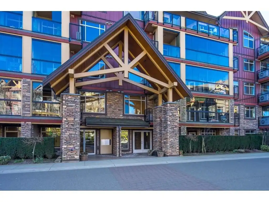 Modern residential condo building with glass balconies and stone accents, featuring a welcoming entrance with wooden structural elements, ideal for Vancouver real estate.