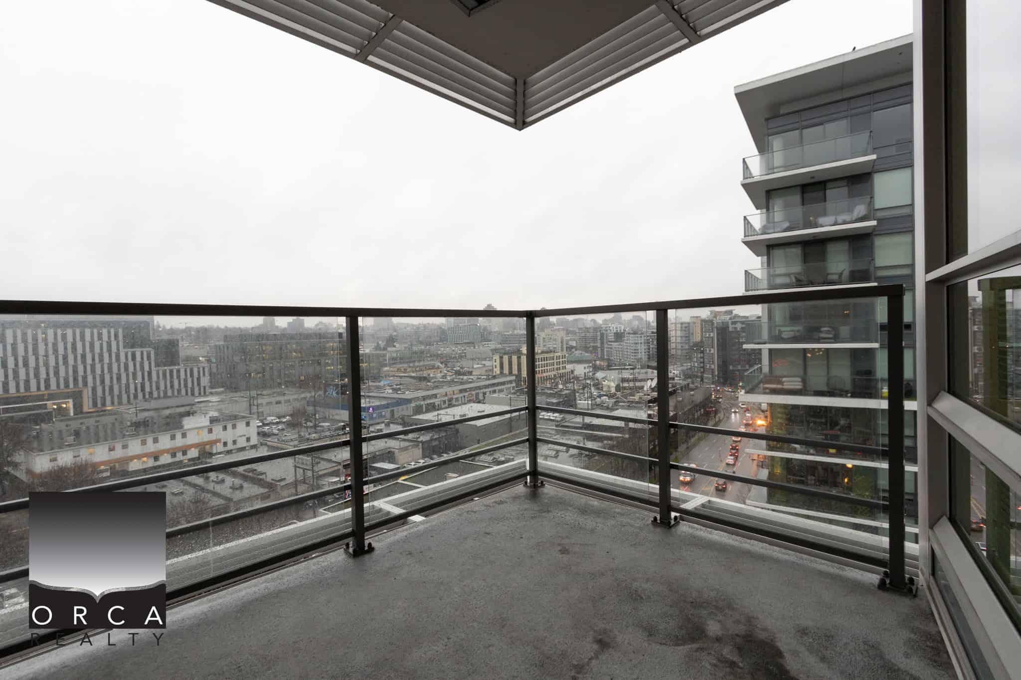 6 (4) Modern downtown Vancouver cityscape viewed from a high-rise balcony on a rainy day, showcasing contemporary urban living with scenic skyline views and glass balcony railing for premium real estate appeal.