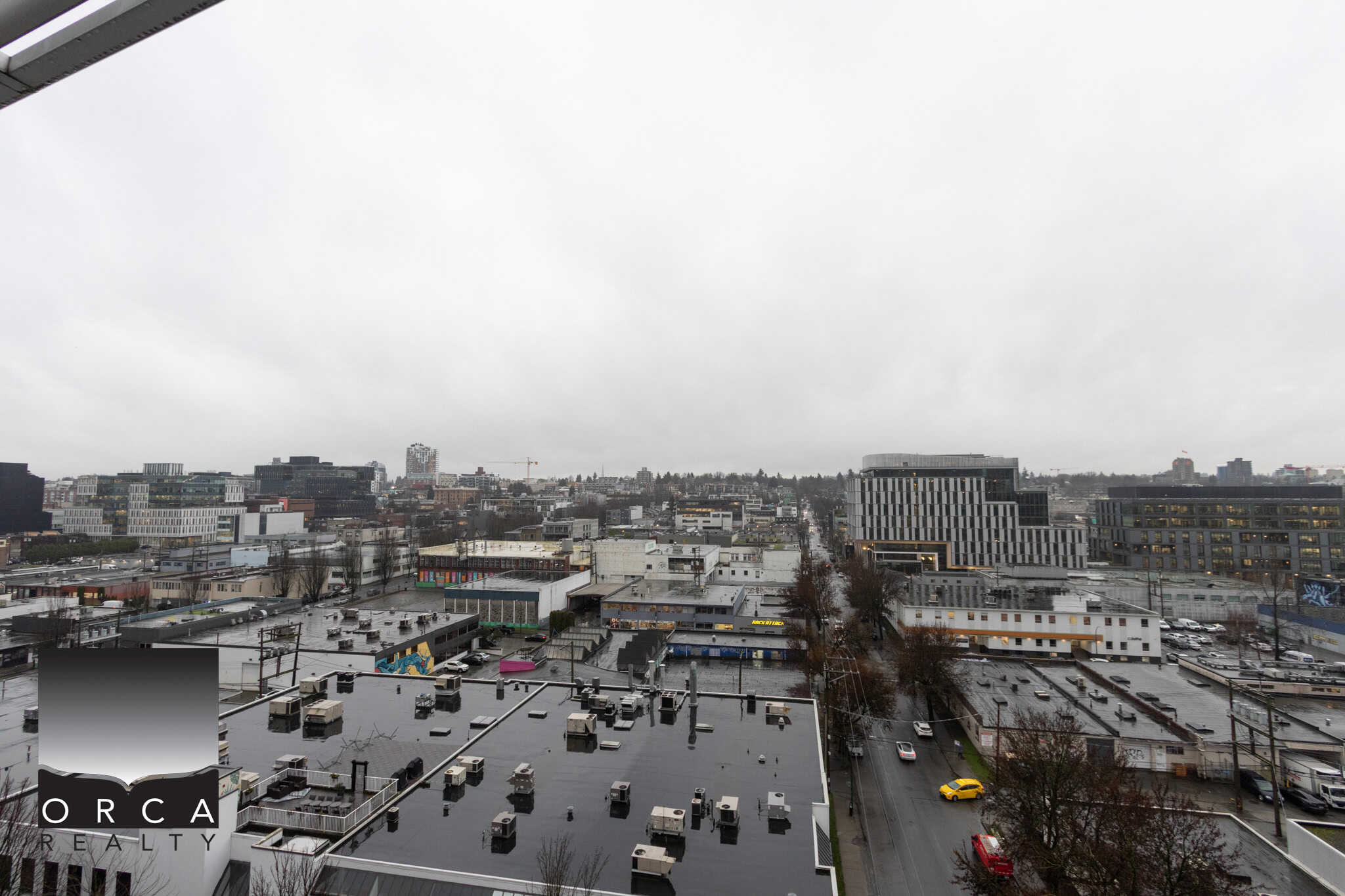 7 (4) Overcast cityscape view of downtown Vancouver from a high-rise building, showcasing commercial rooftops, modern office buildings, and busy streets on a cloudy day, highlighting urban real estate opportunities.