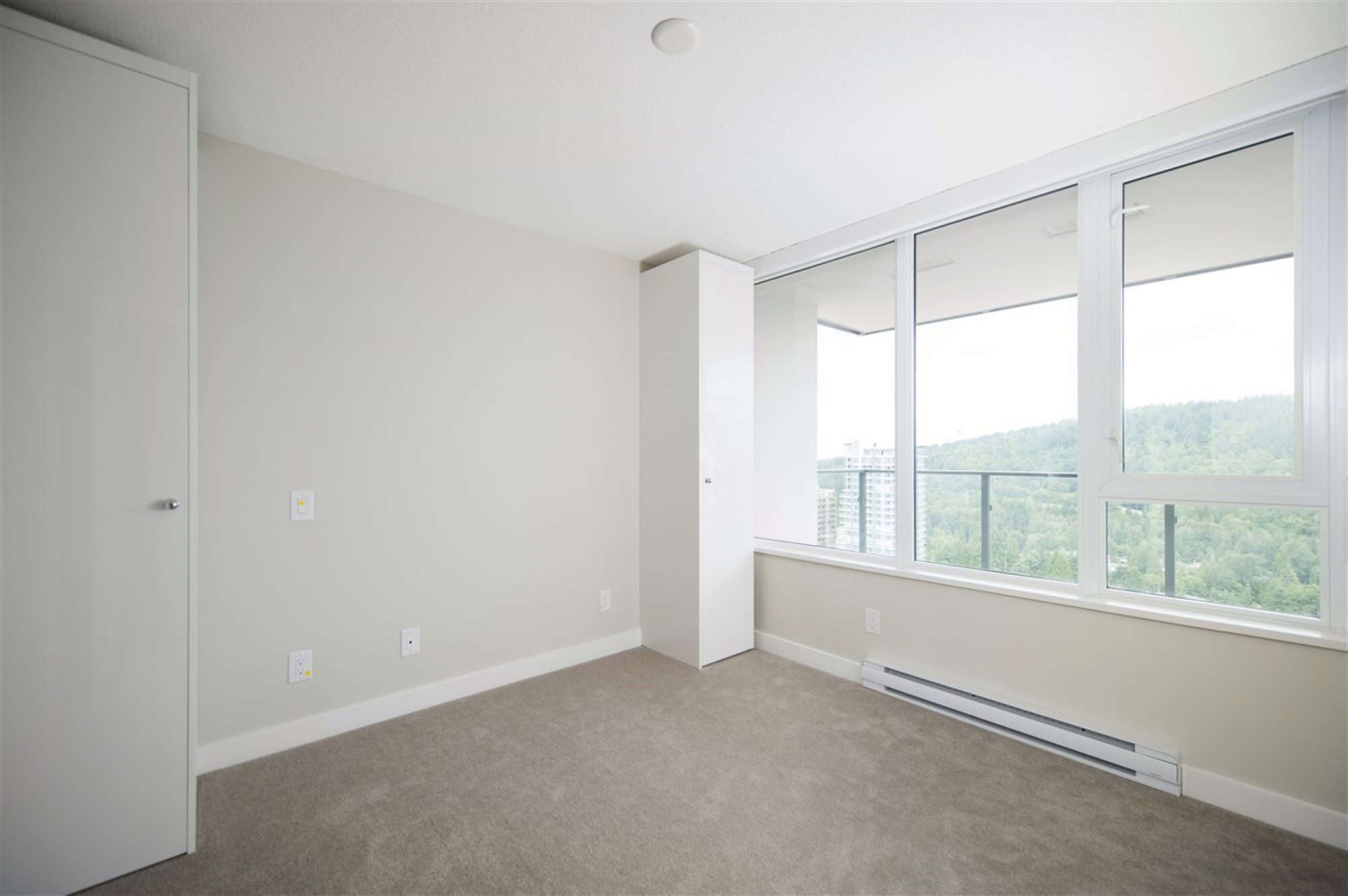 Bright, spacious condo room with large windows showcasing panoramic city and mountain views, perfect for urban living in Vancouver's vibrant real estate market.