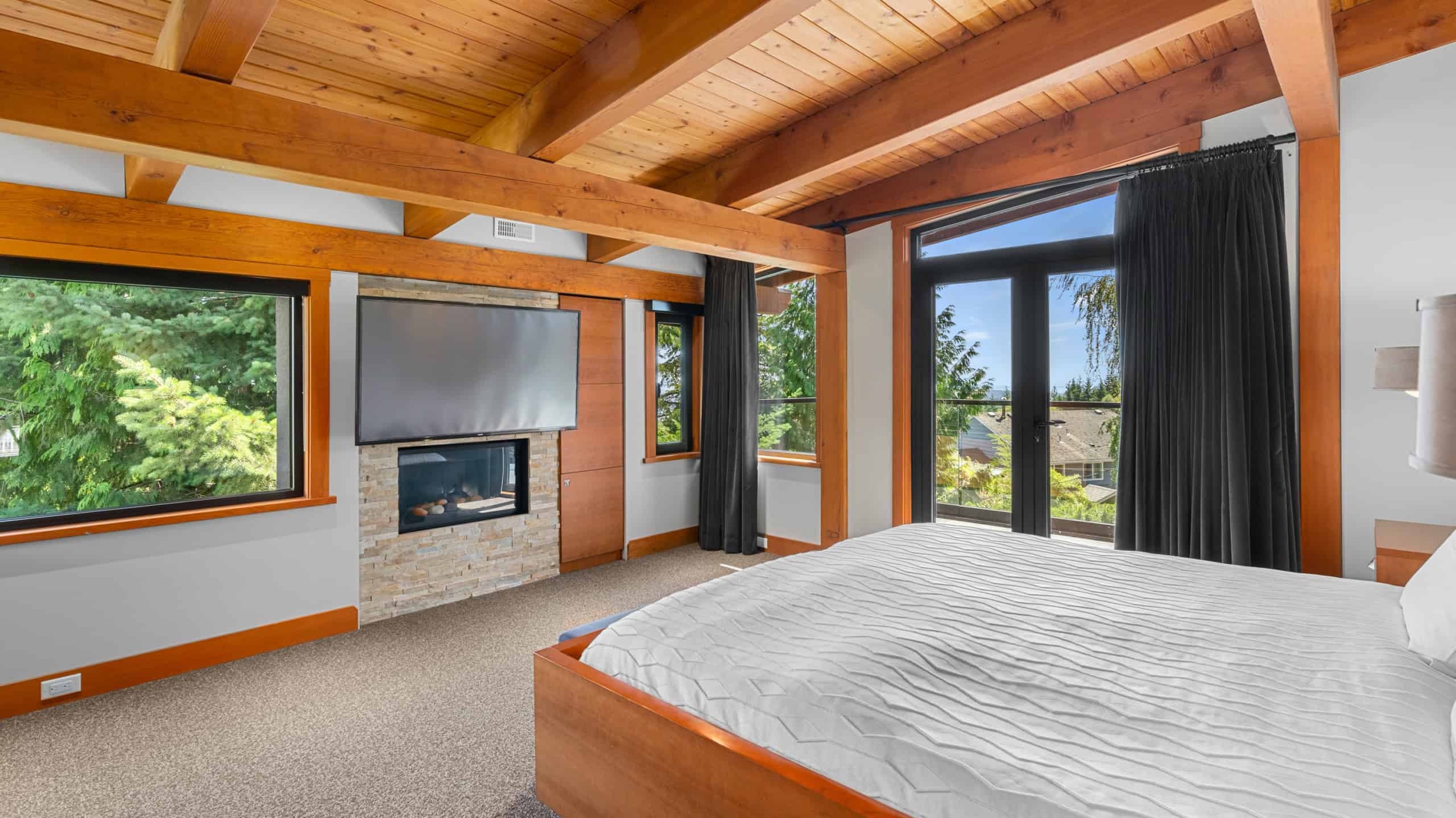 Modern bedroom with wood accents in West Vancouver Bright and spacious bedroom featuring large windows, wood ceiling beams, and modern decor in West Vancouver home. Perfect for relaxing and enjoying scenic views.