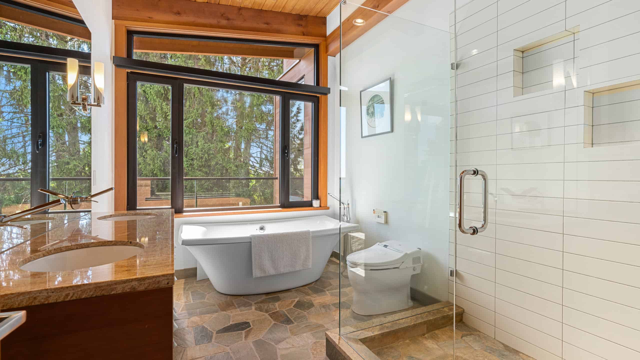 Modern Bathroom with Forest View Luxurious bathroom featuring a freestanding tub and walk-in shower with glass enclosure, overlooking lush greenery in West Vancouver. Perfect for relaxing and enjoying nature.