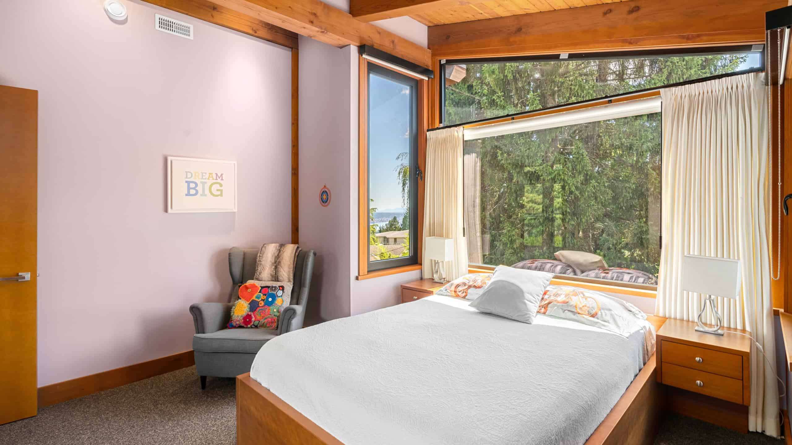 Modern West Vancouver Bedroom with Large Windows Bright West Vancouver bedroom featuring expansive windows with scenic forest views, a cozy bed, and contemporary decor, ideal for a peaceful retreat.
