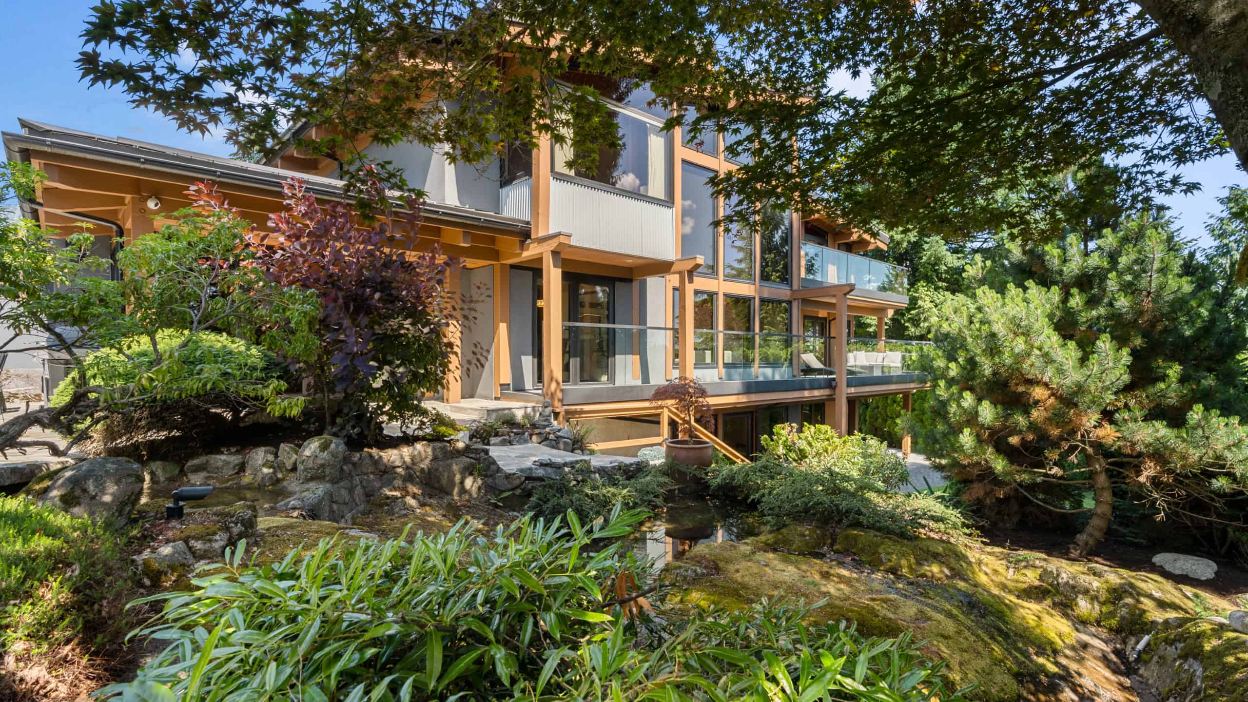 Modern West Vancouver home with lush landscaping and large windows Contemporary West Vancouver residence with extensive garden and natural surroundings, showcasing large windows and outdoor decks.