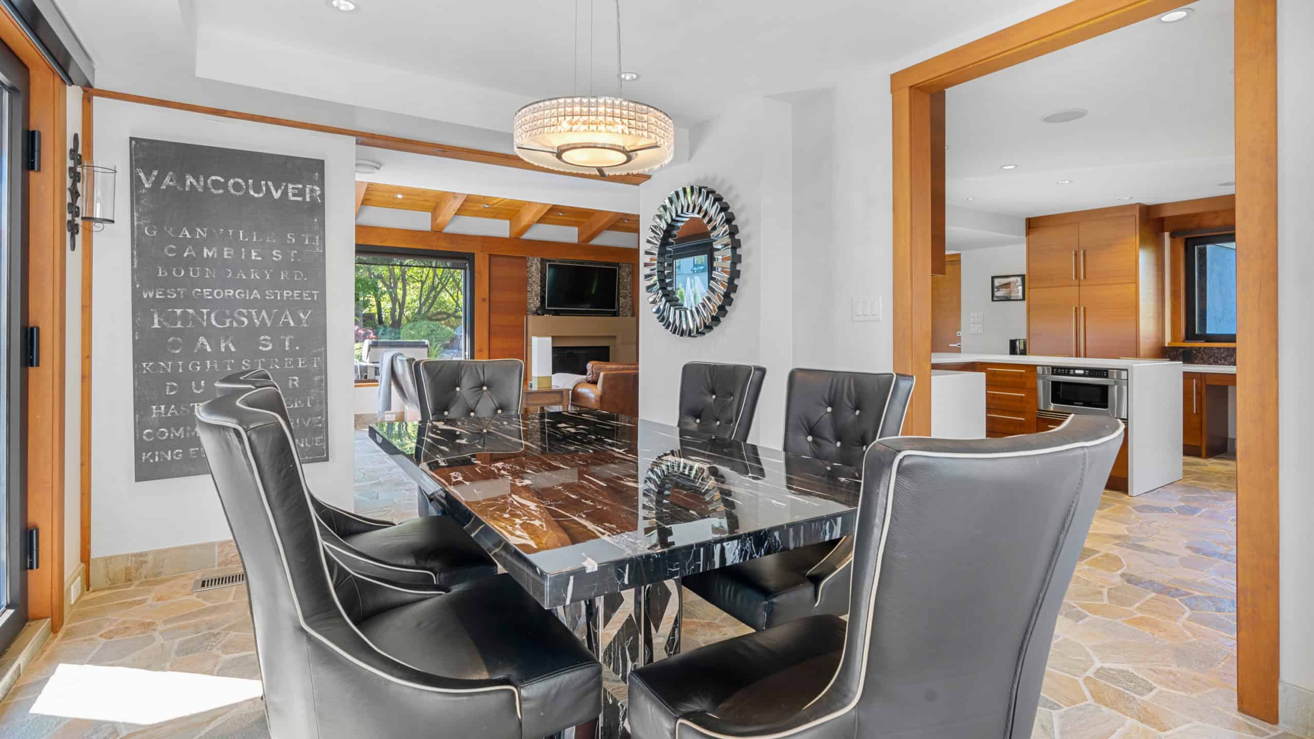 Modern dining room with natural light and stylish decor. Spacious dining area featuring a sleek black table and six comfortable leather chairs, perfect for family gatherings or entertaining guests in West Vancouver.