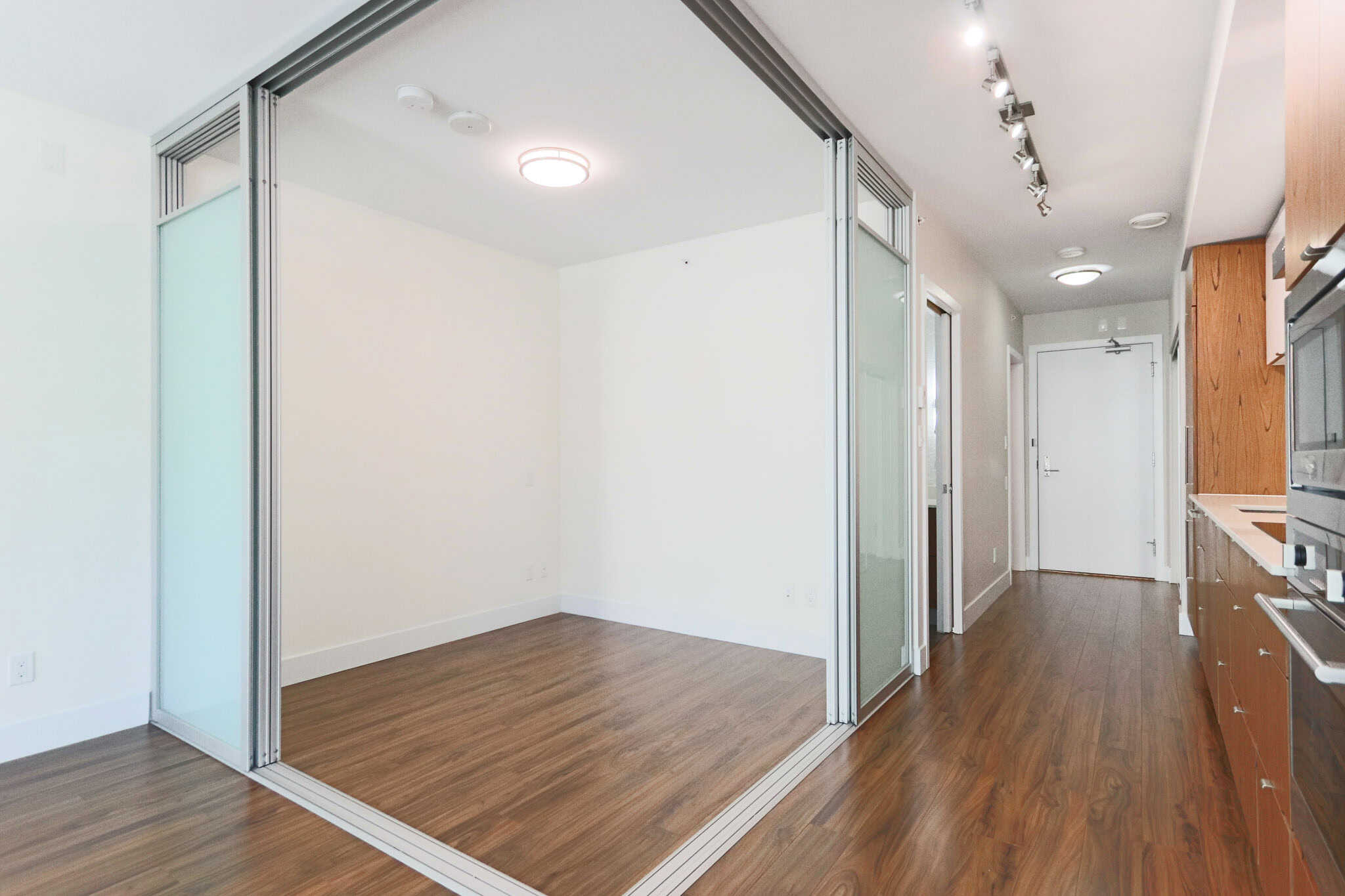 Modern Vancouver-style apartment interior with wooden flooring, open plan kitchen, and sliding glass doors, ideal for homebuyers seeking stylish downtown condos.