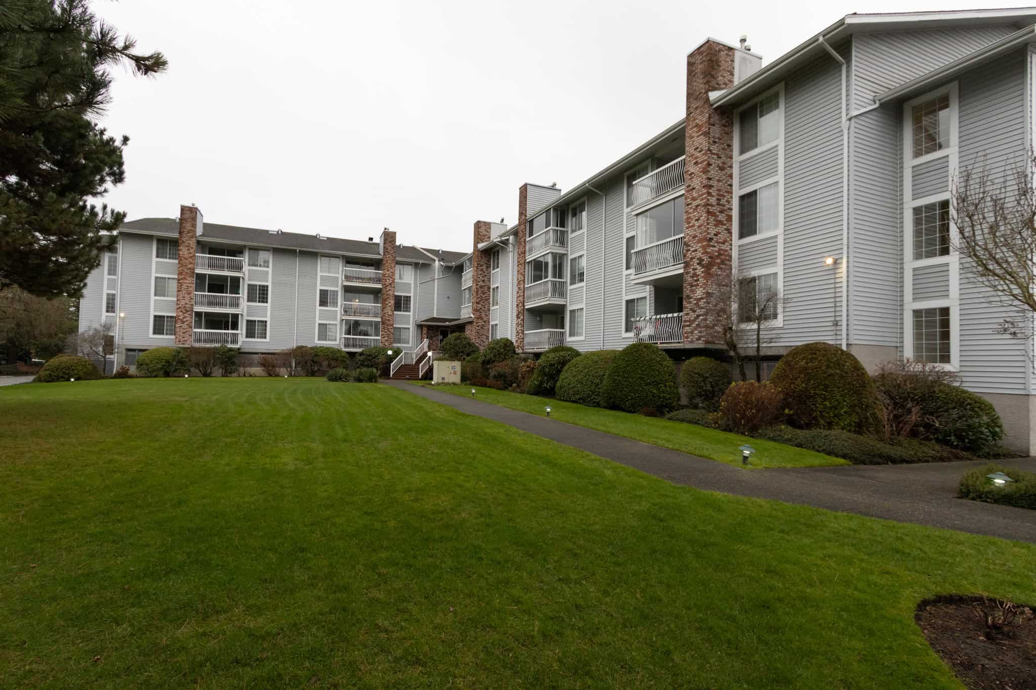 Charming multi-family residential building with manicured lawns and landscaped greenery, offering ideal options for buyers seeking comfortable condos or apartments in the Orca Realty area.