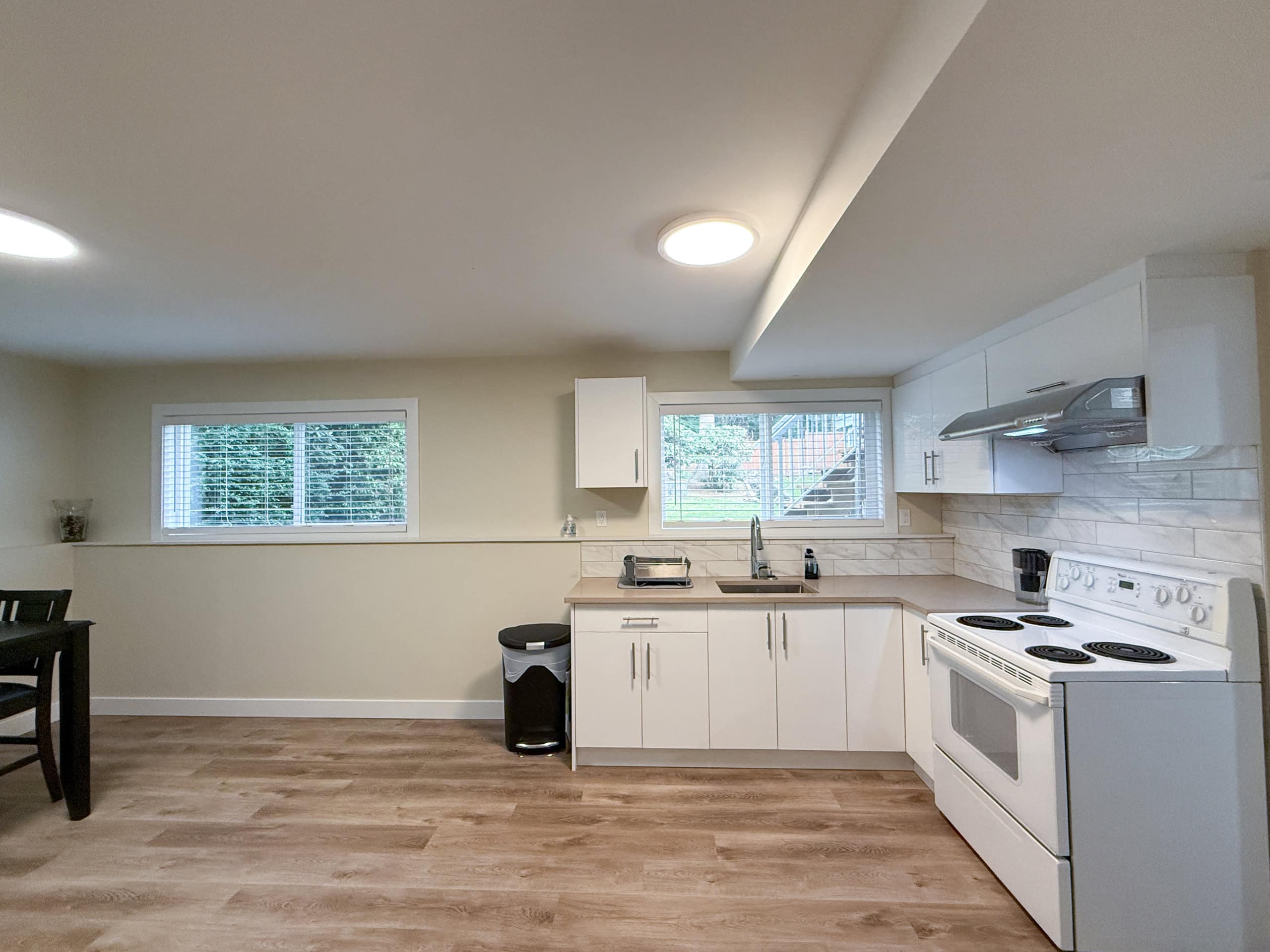Bright and spacious kitchen in North Vancouver featuring white cabinetry, stainless steel sink, and modern appliances, perfect for family living and entertaining.