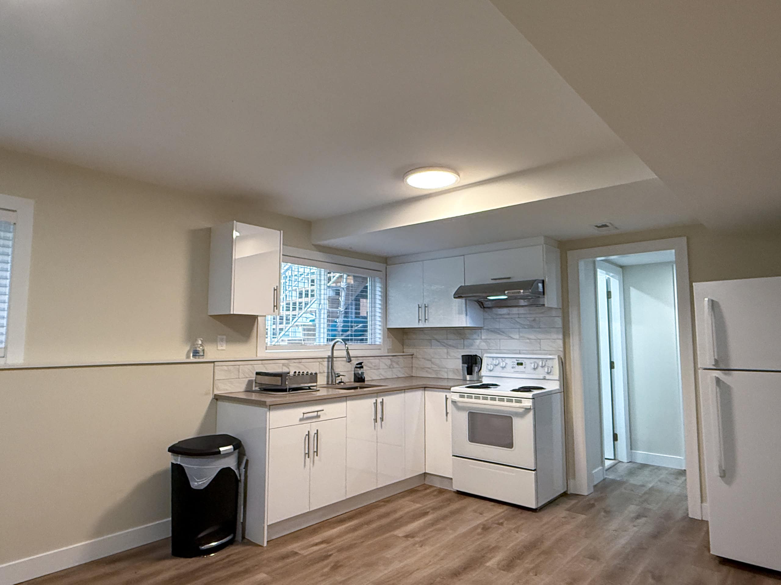 Bright and modern North Vancouver kitchen featuring white cabinetry, a stove, refrigerator, and ample counter space, ideal for family living and entertaining.