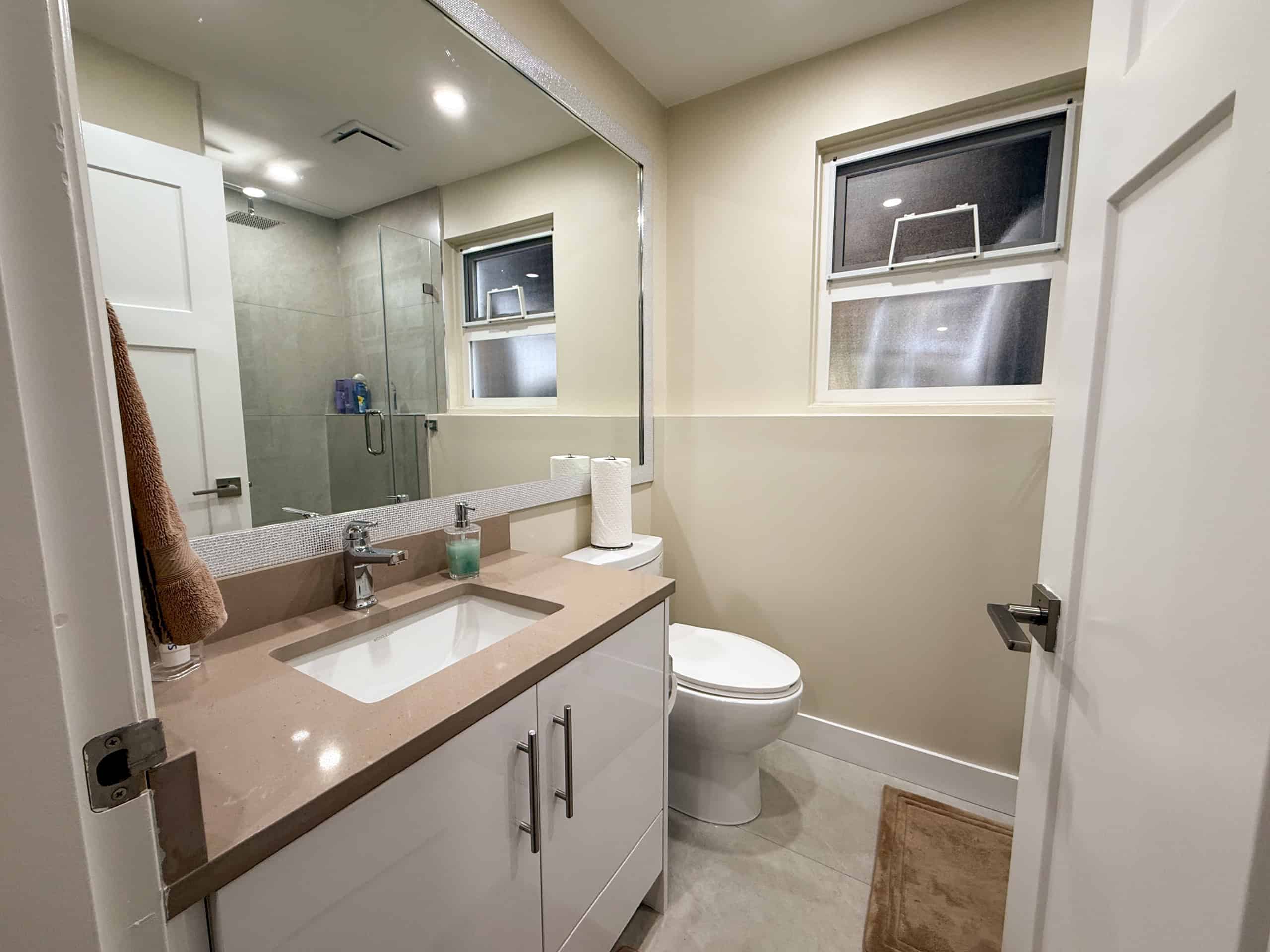 Bright bathroom featuring a sleek vanity, modern fixtures, and a clean toilet in North Vancouver home.
