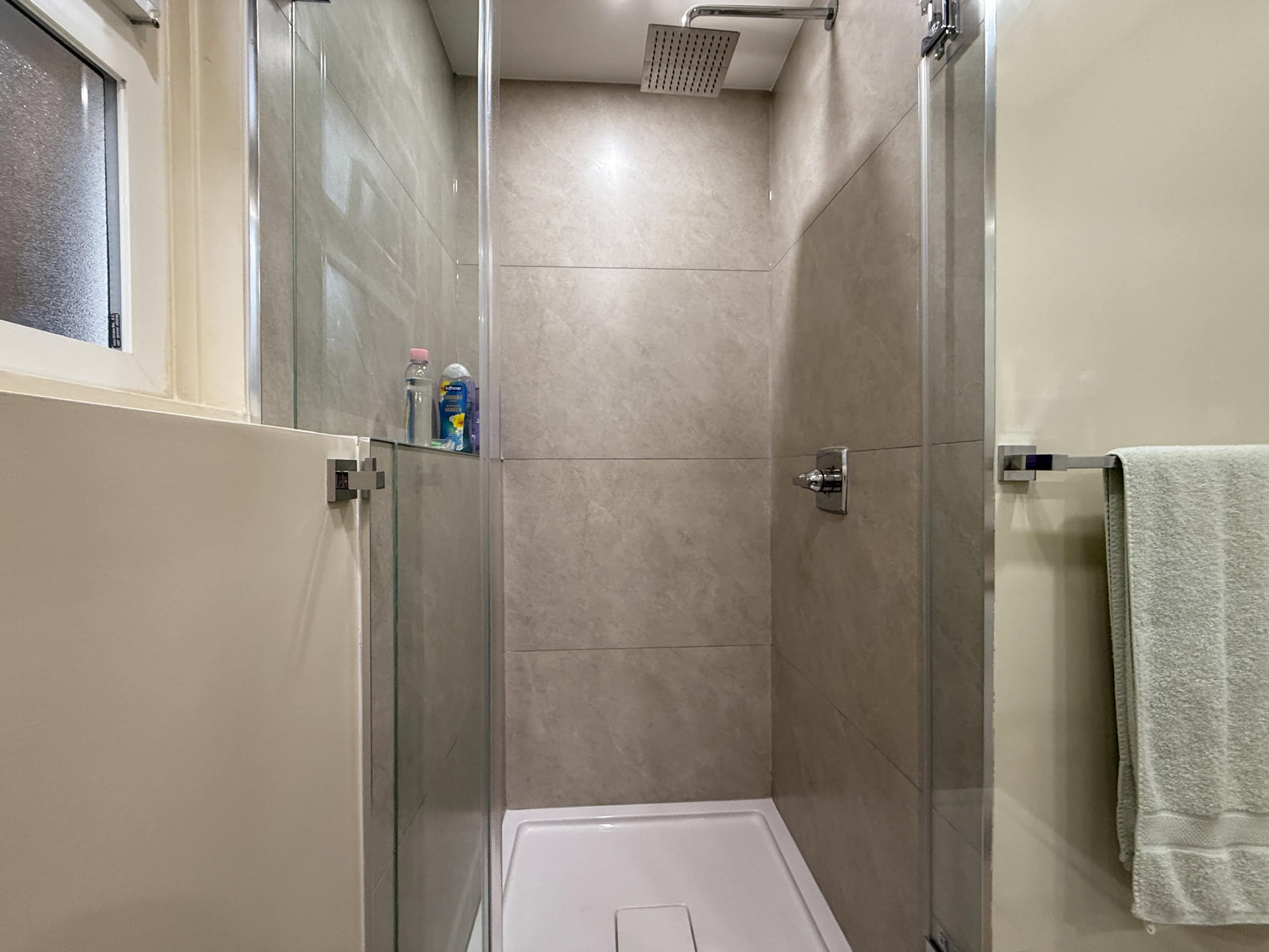 Bright, clean bathroom featuring a spacious walk-in shower with glass doors and contemporary tile work.