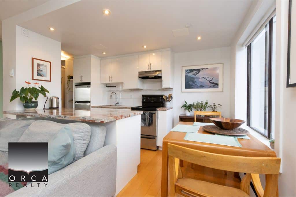 Bright and modern kitchen and dining area in a Vancouver home, featuring white cabinetry, stainless steel appliances, natural light, and cozy decor, perfect for real estate listings.