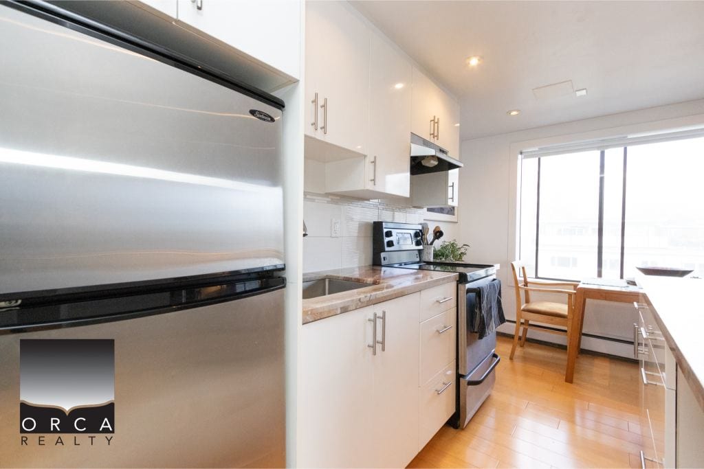 Modern kitchen with stainless steel appliances, bright natural light, and contemporary cabinetry, ideal for Vancouver real estate buyers seeking stylish homes.