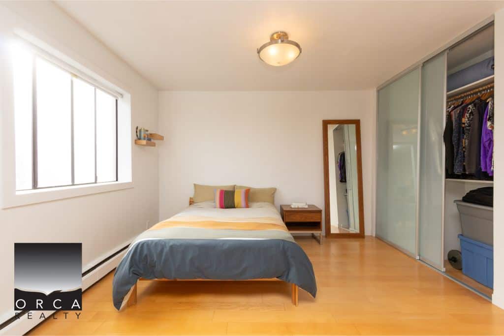 Bright modern bedroom with large window, cozy bed, and spacious closet - ideal for Vancouver real estate buyers.