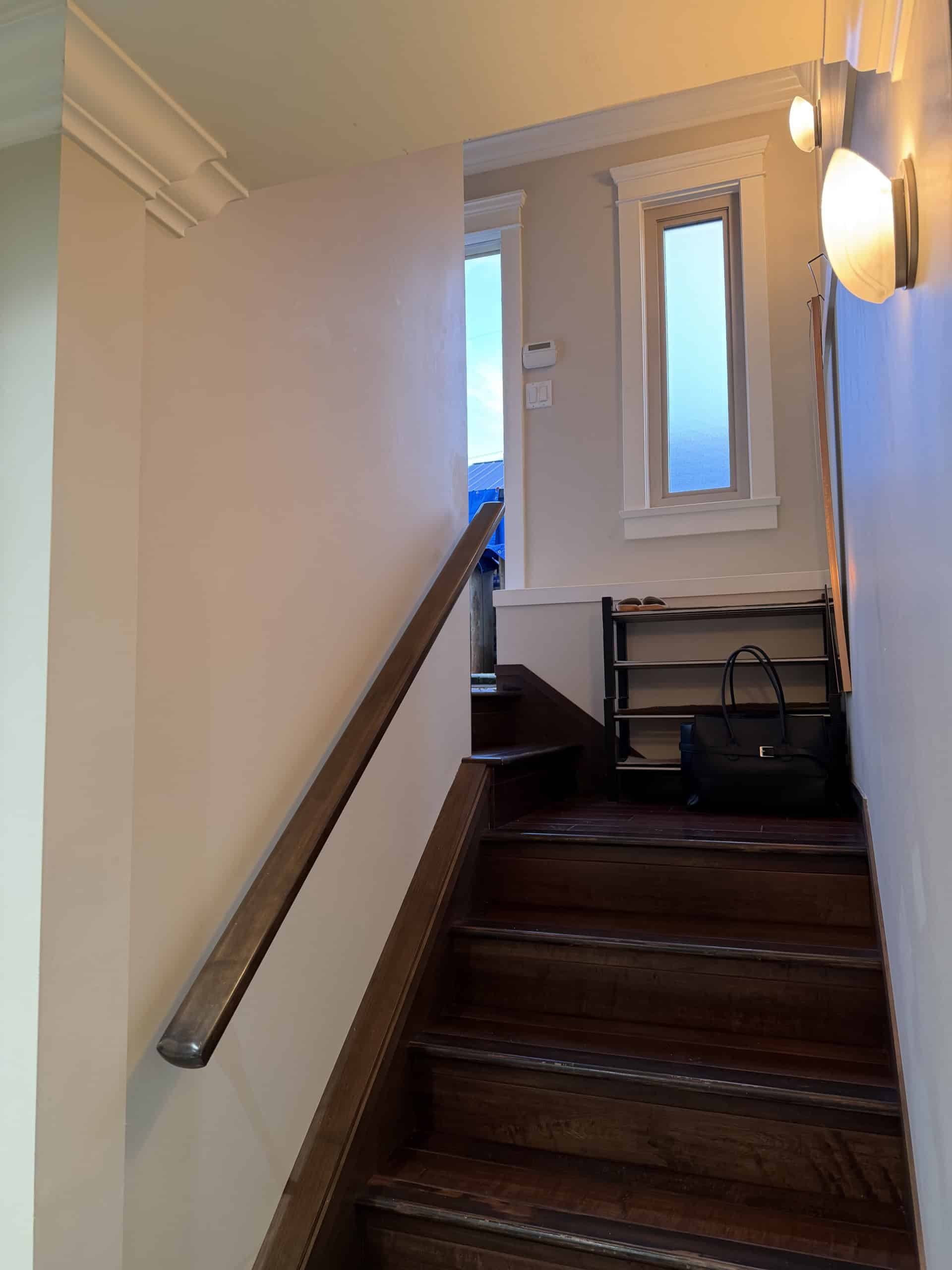 Bright entryway with wooden stairs and natural light from tall windows, showcasing cozy, stylish interior design perfect for Vancouver area homes.