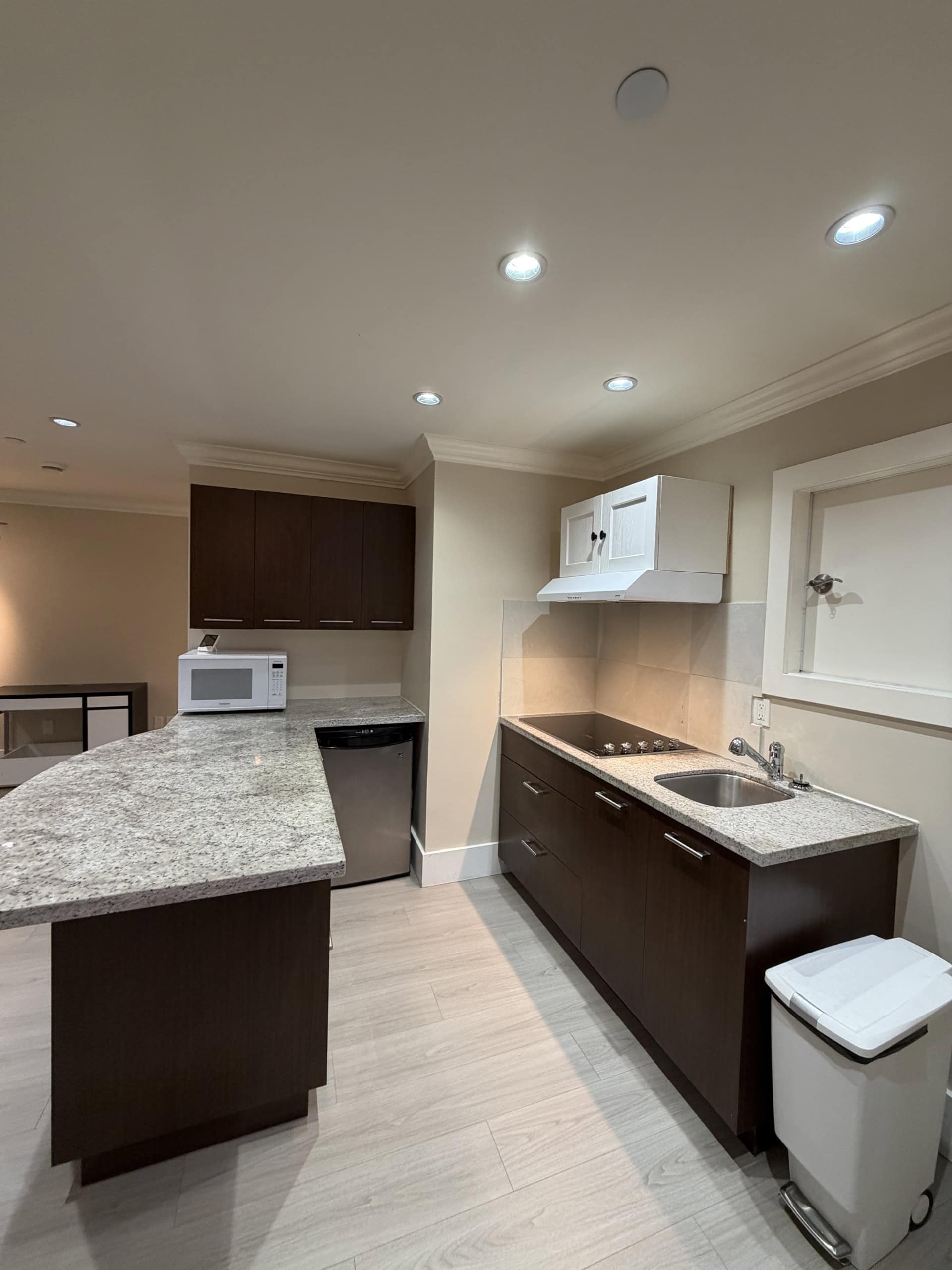 Bright modern kitchen with granite countertops, white and dark wood cabinets, stainless steel appliances, and a cozy atmosphere perfect for home cooking. Ideal for Vancouver real estate buyers.
