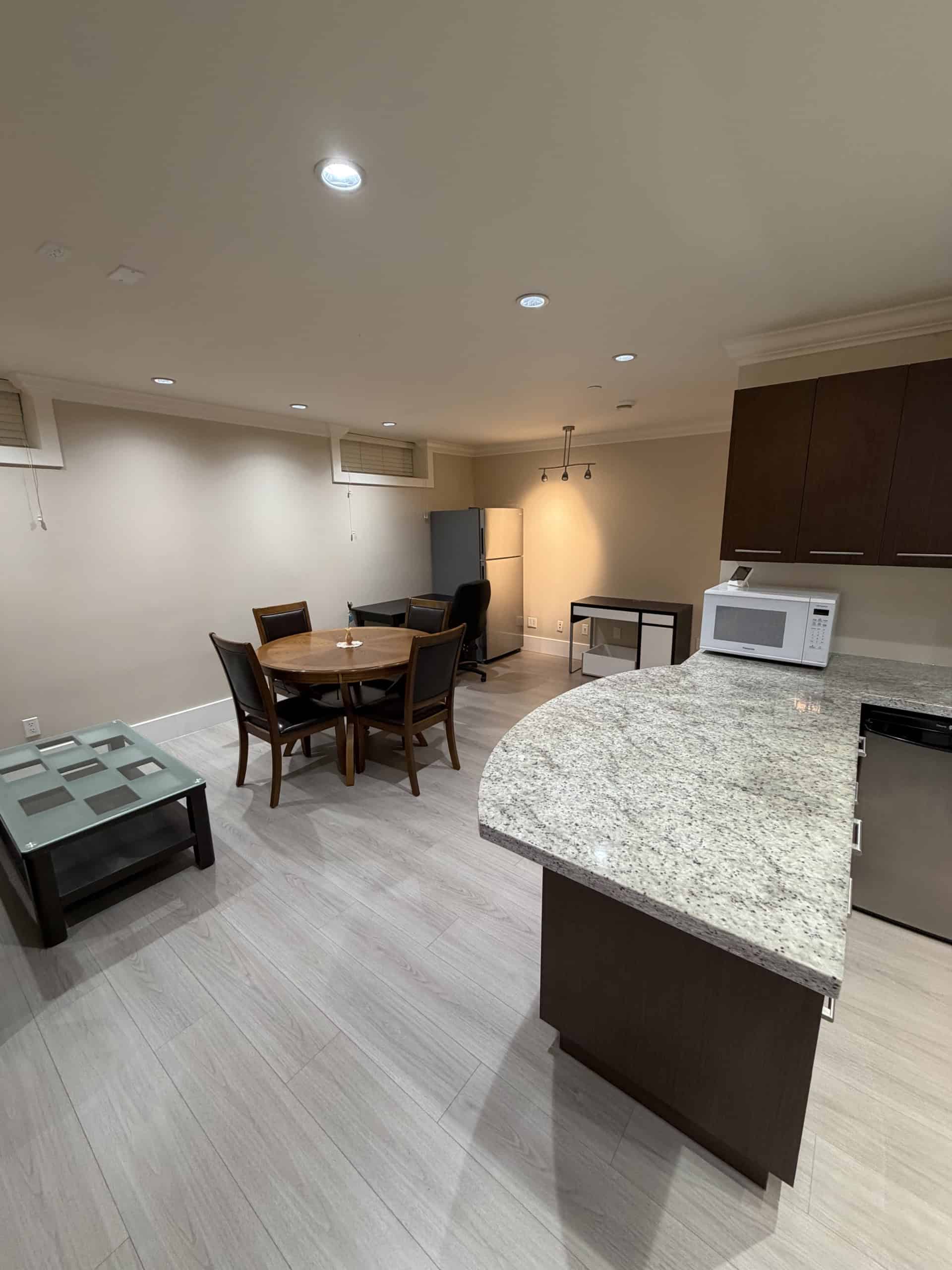 Spacious modern kitchen and dining area in an upscale condo, featuring granite countertops, wooden cabinetry, stainless steel appliances, and ample space for family meals and entertaining.