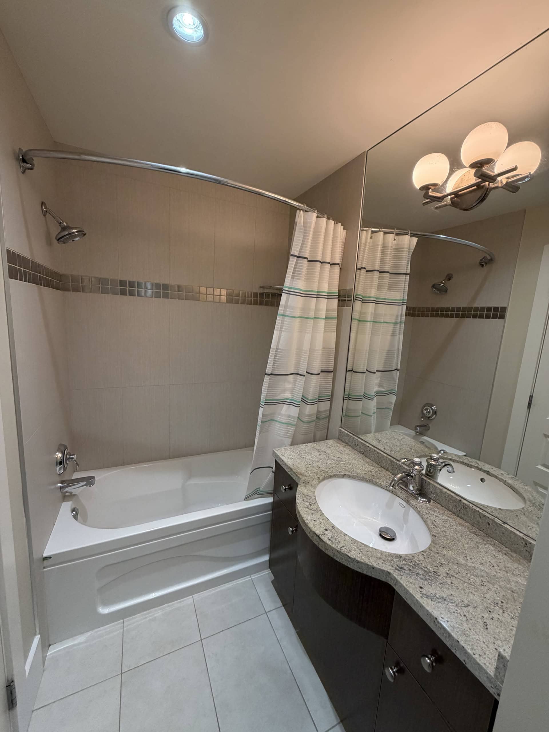 Bright modern bathroom with a bathtub and shower combo, granite countertop sink, and large mirror, showcasing quality fixtures and stylish design, ideal for Vancouver homes.