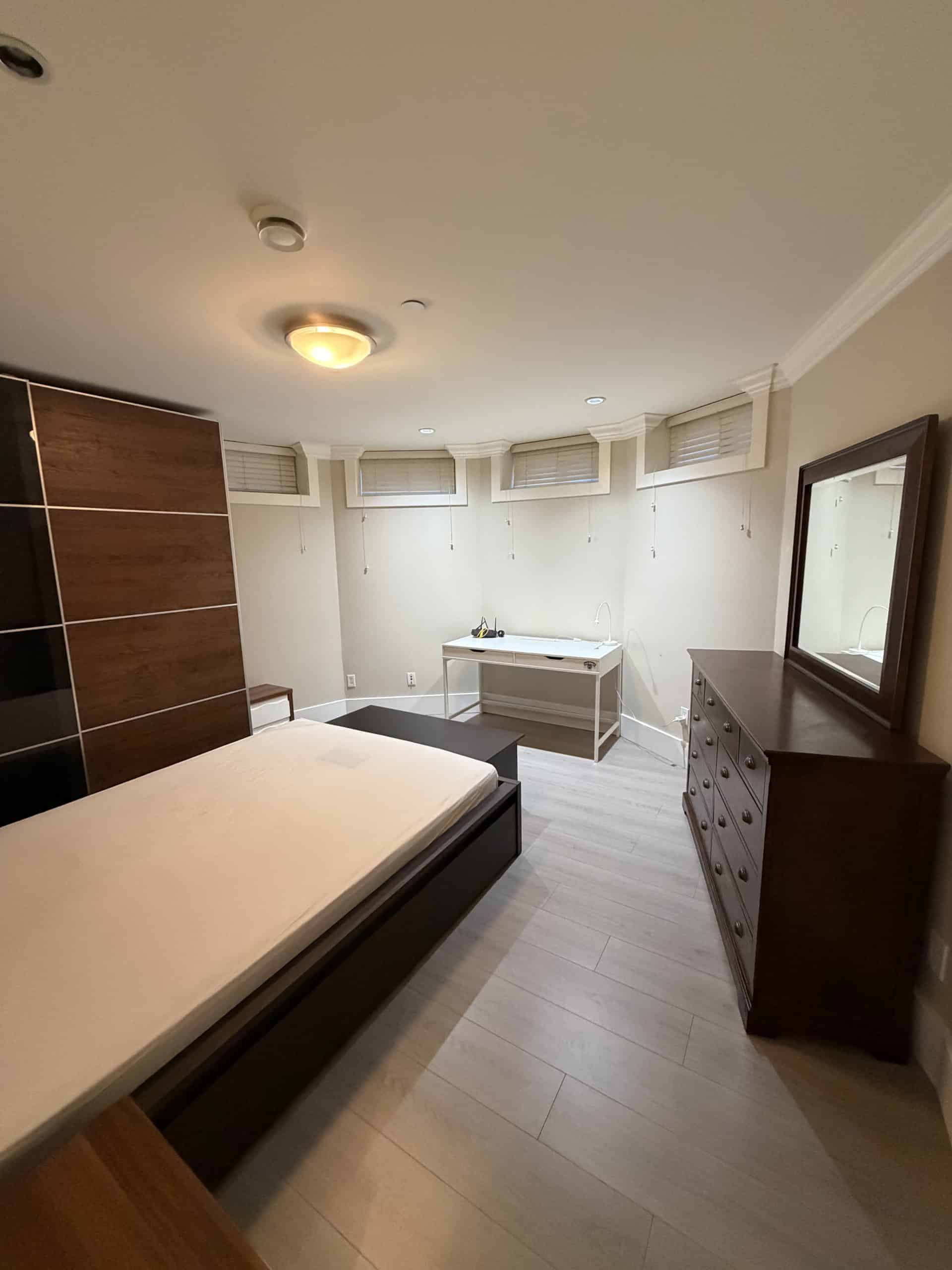 Bright spacious bedroom with modern furnishings, large windows with blinds, hardwood flooring, and ample closet space, perfect for Vancouver real estate buyers.