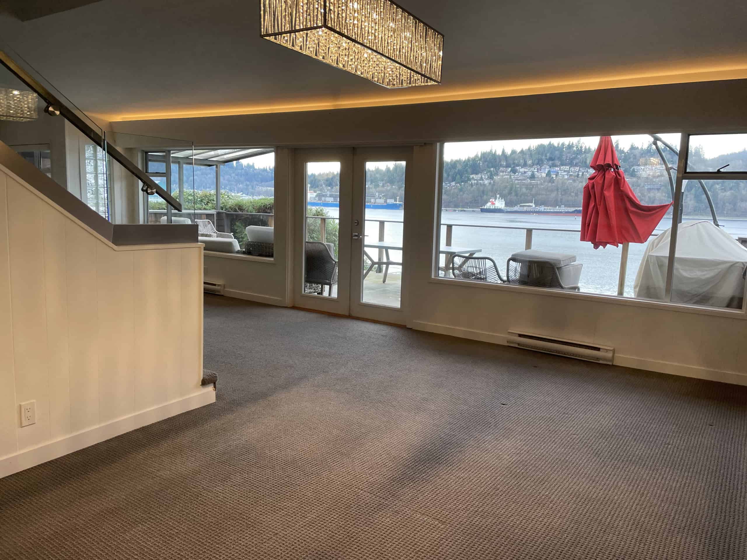 Stunning waterfront view from a luxury seaside condo, featuring spacious living area and balcony overlooking the water, perfect for oceanfront property investment in British Columbia.