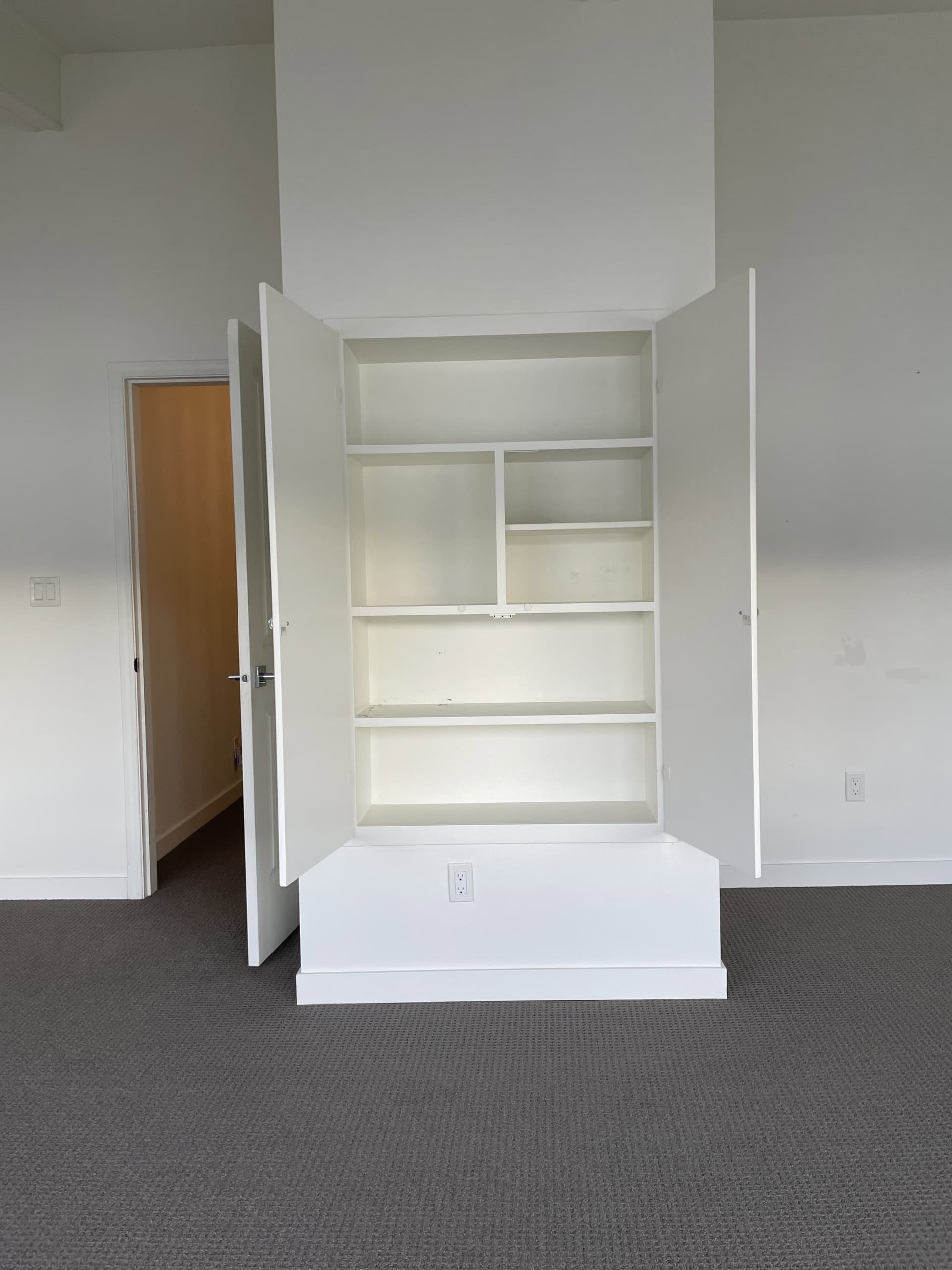 Bright white built-in shelves and cabinets in a modern residential interior, showcasing stylish storage solutions by Orca Realty Inc.