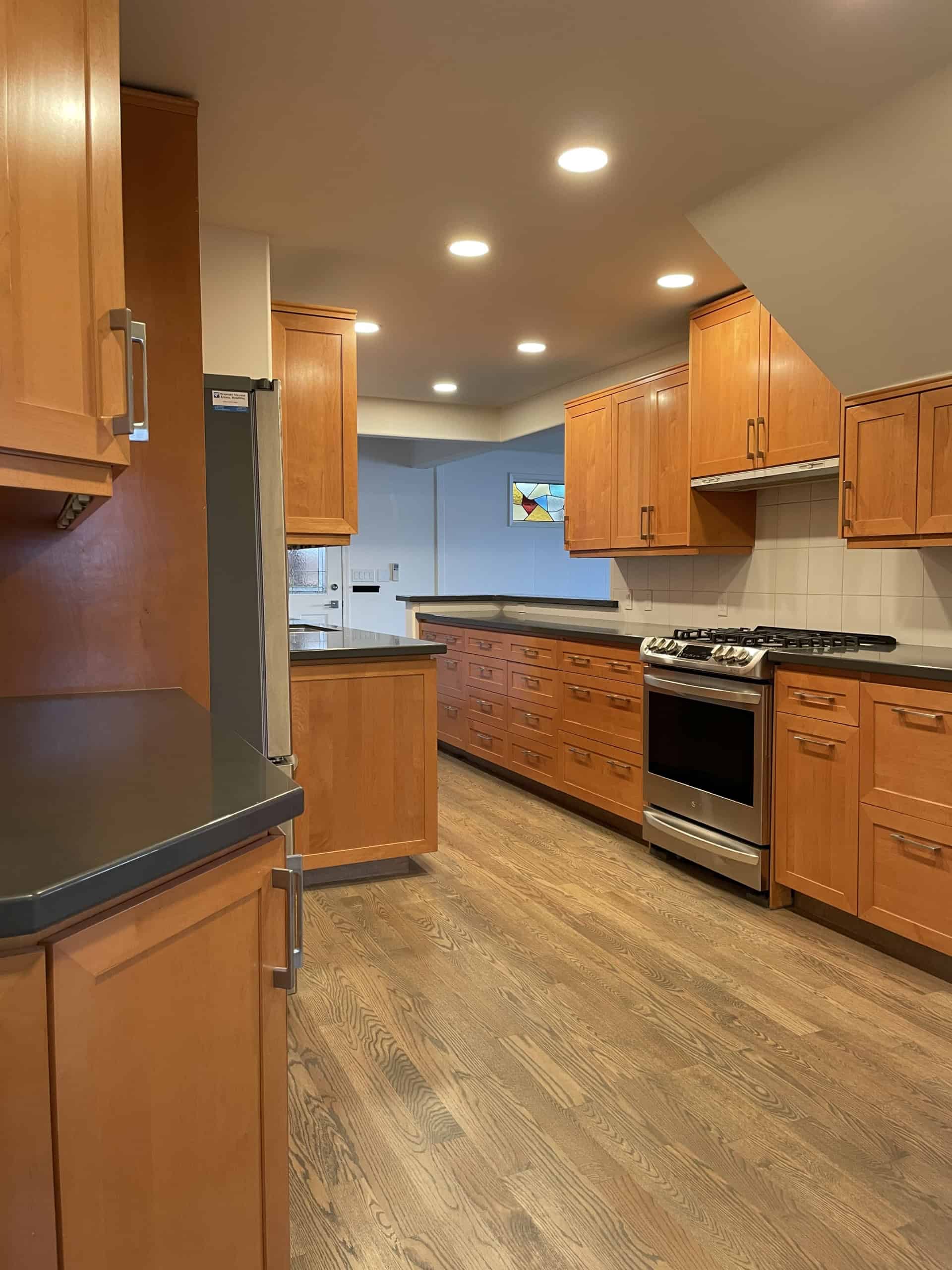 Spacious modern kitchen with wooden cabinetry, stainless steel appliances, and hardwood flooring, ideal for Vancouver real estate and realtors.