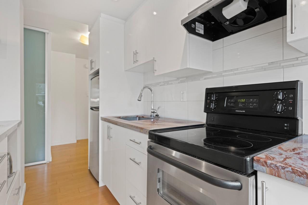 Modern kitchen with white cabinetry, stainless steel appliances, and granite countertops, perfect for Toronto real estate buyers seeking stylish and functional homes.