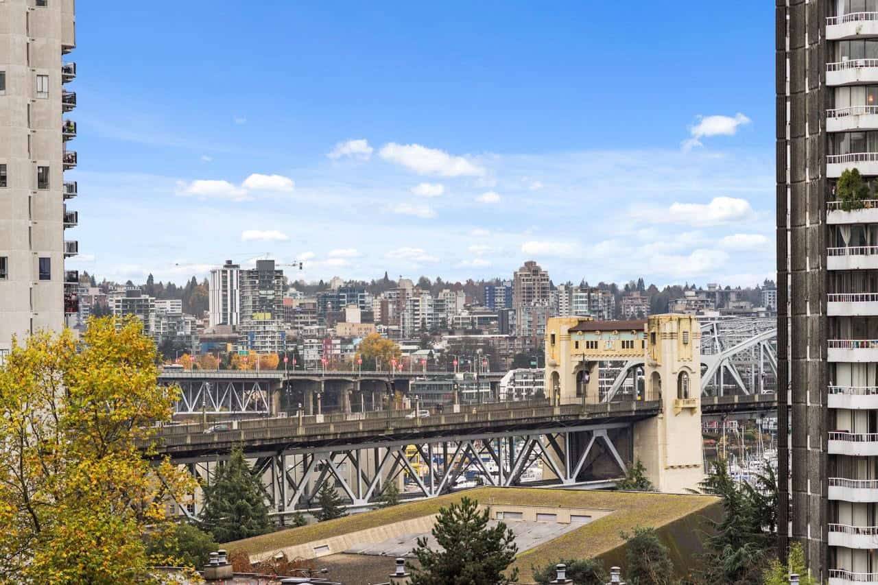 Vibrant cityscape view featuring urban high-rise buildings and the Seattle skyline, captured from a residential area with trees and a bridge, showcasing the dynamic real estate market in Seattle, Washington.