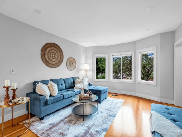 Bright and inviting living room with large windows, modern blue sofas, and stylish decor in a Vancouver residence. Perfect space for relaxation and entertaining guests.