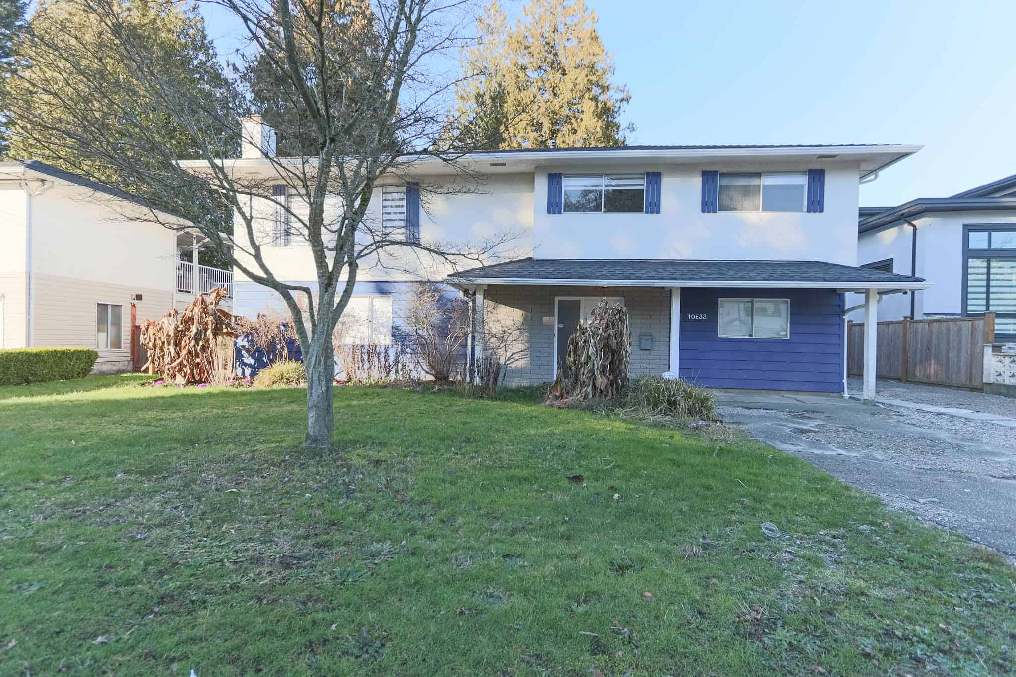 Exterior view of a two-story house in Delta with a spacious front yard, mature trees, and a driveway, showcasing a family-friendly residential property.
