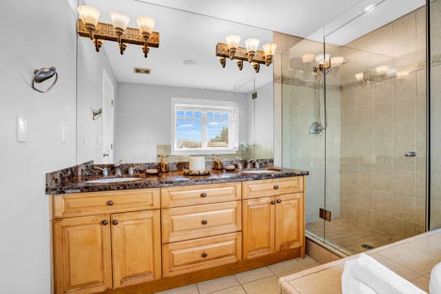Elegant West Vancouver bathroom featuring a double vanity with granite countertop, modern lighting fixtures, and a spacious glass-enclosed shower. Perfect for luxury home living.