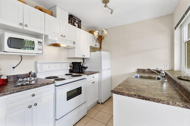 Bright and functional kitchen in West Vancouver with white cabinets, modern appliances, and ample counter space, perfect for family living.