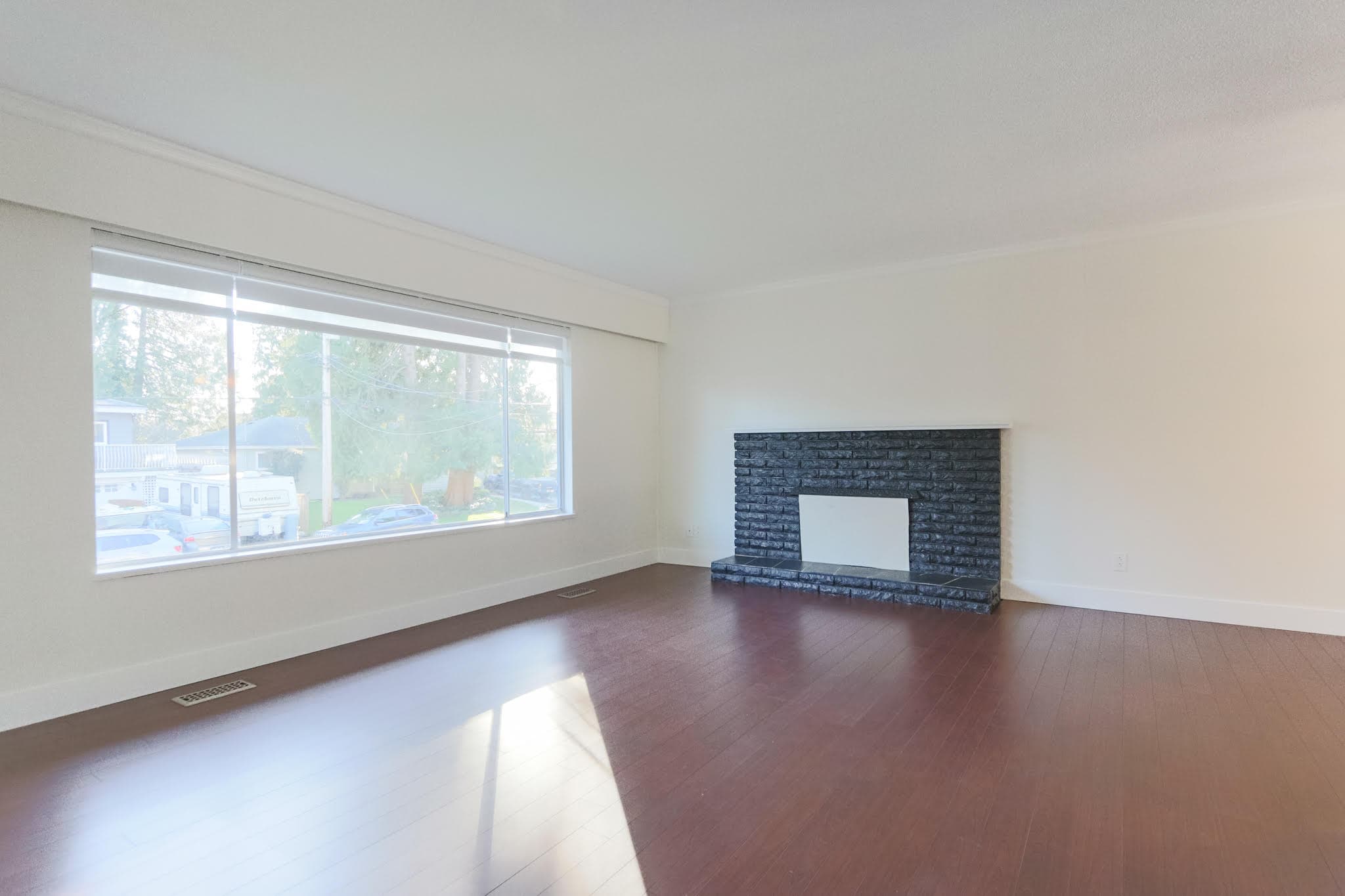 Bright and airy upstairs living room with large window and modern fireplace in Delta property. Perfect for relaxing or entertaining in a comfortable, open space.