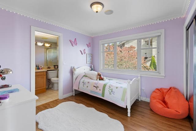 Bright bedroom with lavender walls, butterfly decor, and large window overlooking the neighborhood. Perfect for family living in the West Vancouver area.