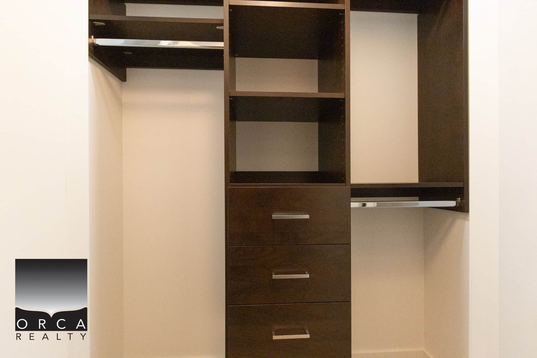 In closet with dark wood shelving and drawers, ideal for organizing clothing and accessories in Vancouver.