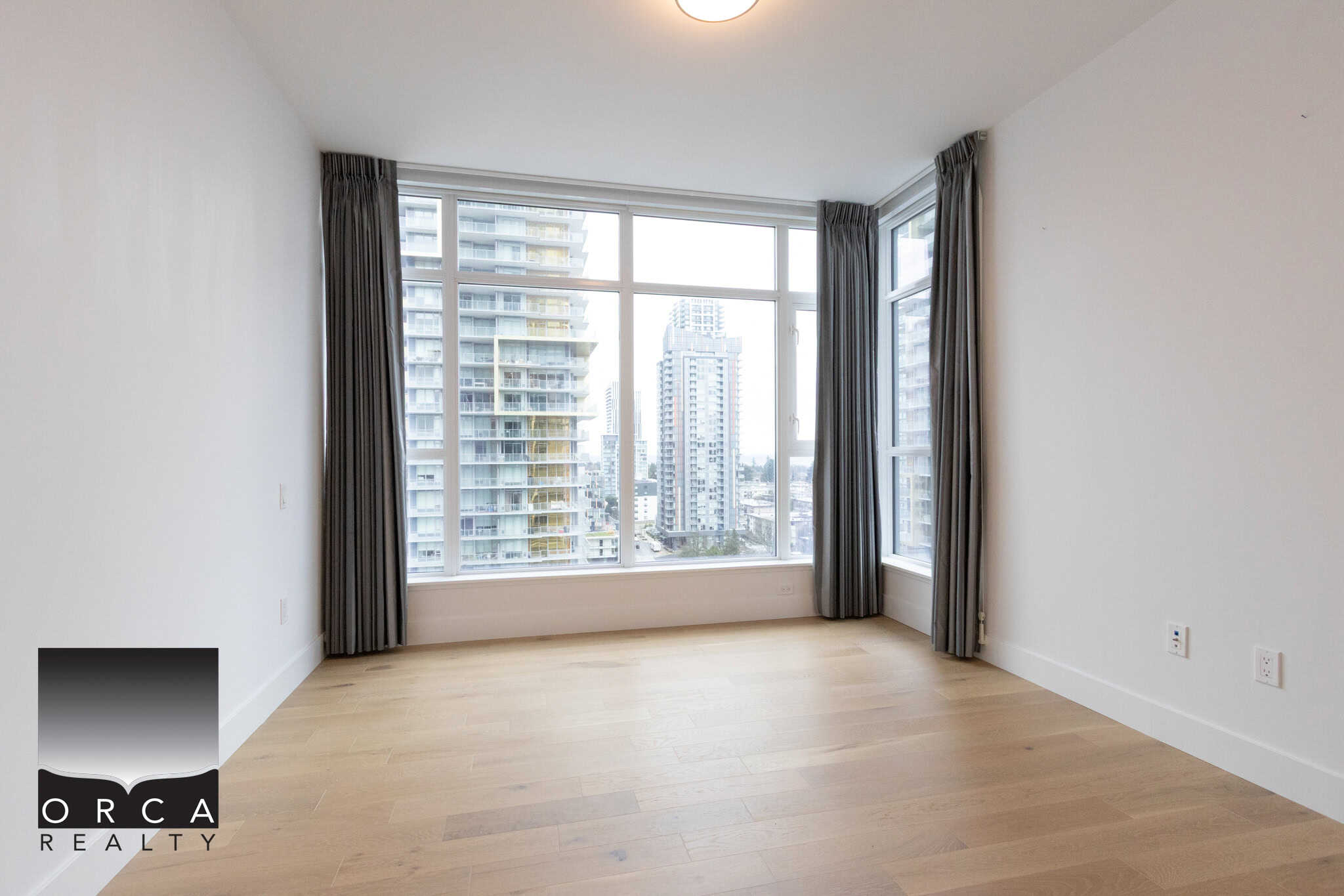 Bright, spacious living room in Vancouver apartment with large windows showcasing downtown skyline and natural light. Perfect for urban lifestyle and comfort.