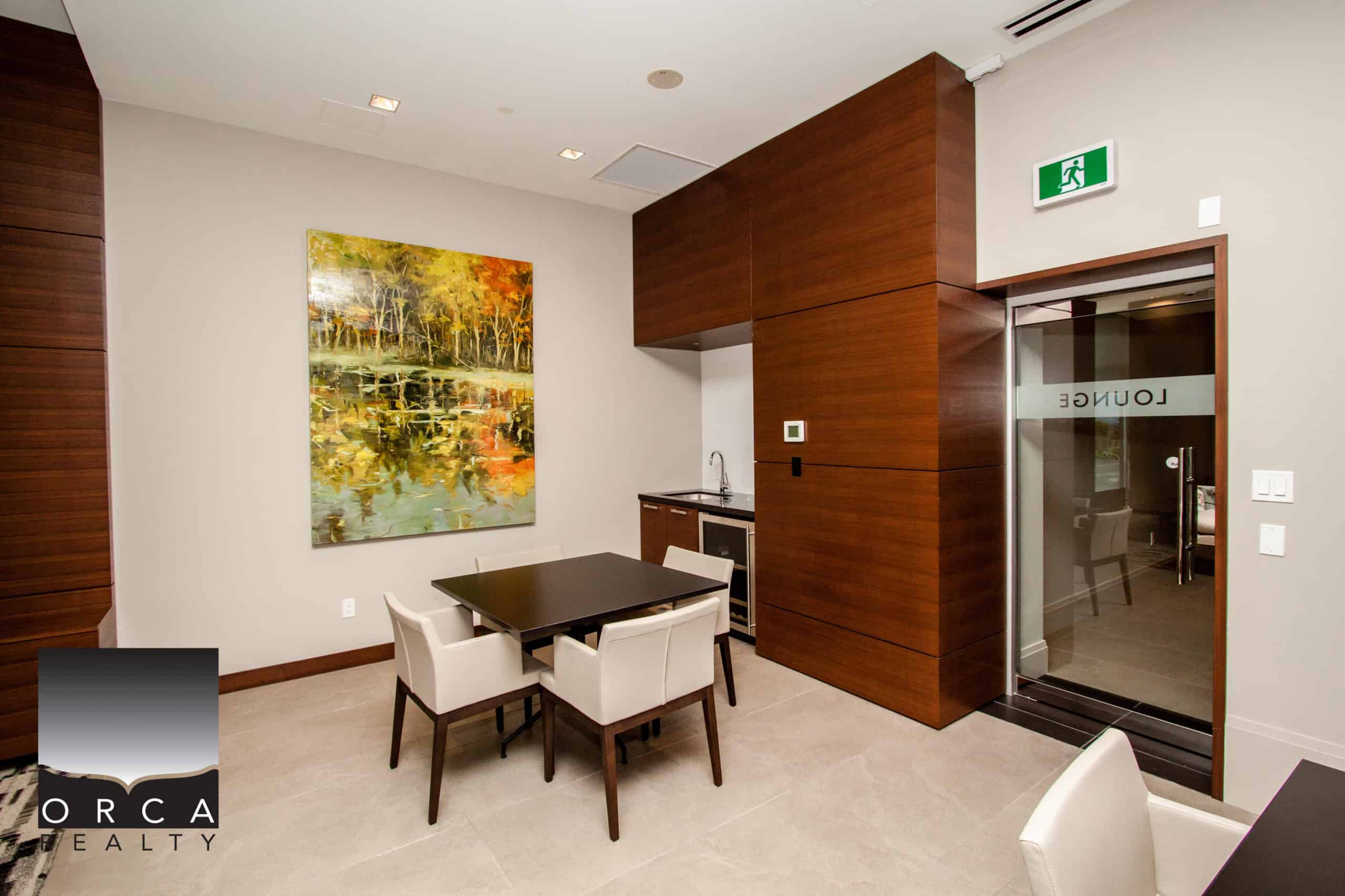 Interior view of a contemporary Vancouver condo featuring a dining area with a dark wood table, white chairs, and a colorful landscape painting on the wall.