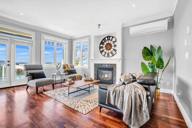 Spacious living room in a West Vancouver home with large windows, hardwood floors, modern fireplace, and stylish furniture, offering a bright and inviting atmosphere.