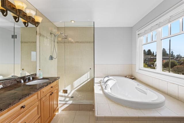 Spacious bathroom with large bathtub and walk-in shower in a West Vancouver residence. Modern design, natural light, and high-end finishes highlight luxury living.