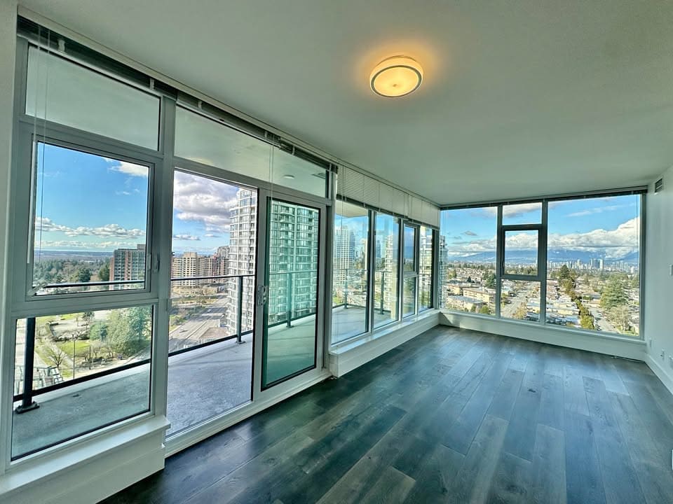 Bright, spacious living room with floor-to-ceiling windows showcasing urban scenery.